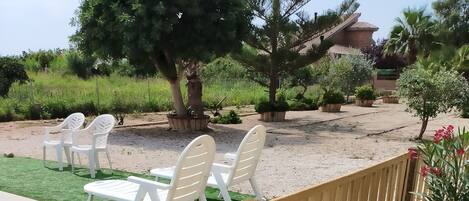 Una valla de madera con un camino de grava y sillas de plástico blancas.