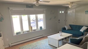 A living room with a blue sofa, a white coffee table, and a teal couch. - Cozy home, quiet neighborhood, near OOB attractions! (Old Orchard Beach)