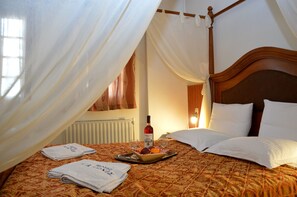 A bed with a canopy, a bottle of wine, glasses, and towels on a tray.