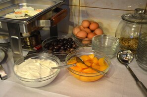 A buffet with various food items including eggs, olives, and fruits.