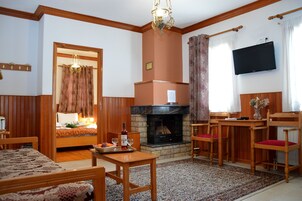Una sala de estar con chimenea, muebles de madera, televisor y candelabro.