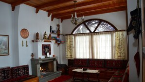 A traditional room with a fireplace, wooden benches, and a large window with curtains.