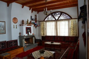 Una habitación tradicional con chimenea, bancos de madera y un ventanal con cortinas.