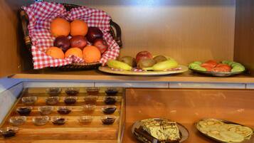 Un bufé con diversas frutas, una selección de postres y varios recipientes pequeños con salsas.