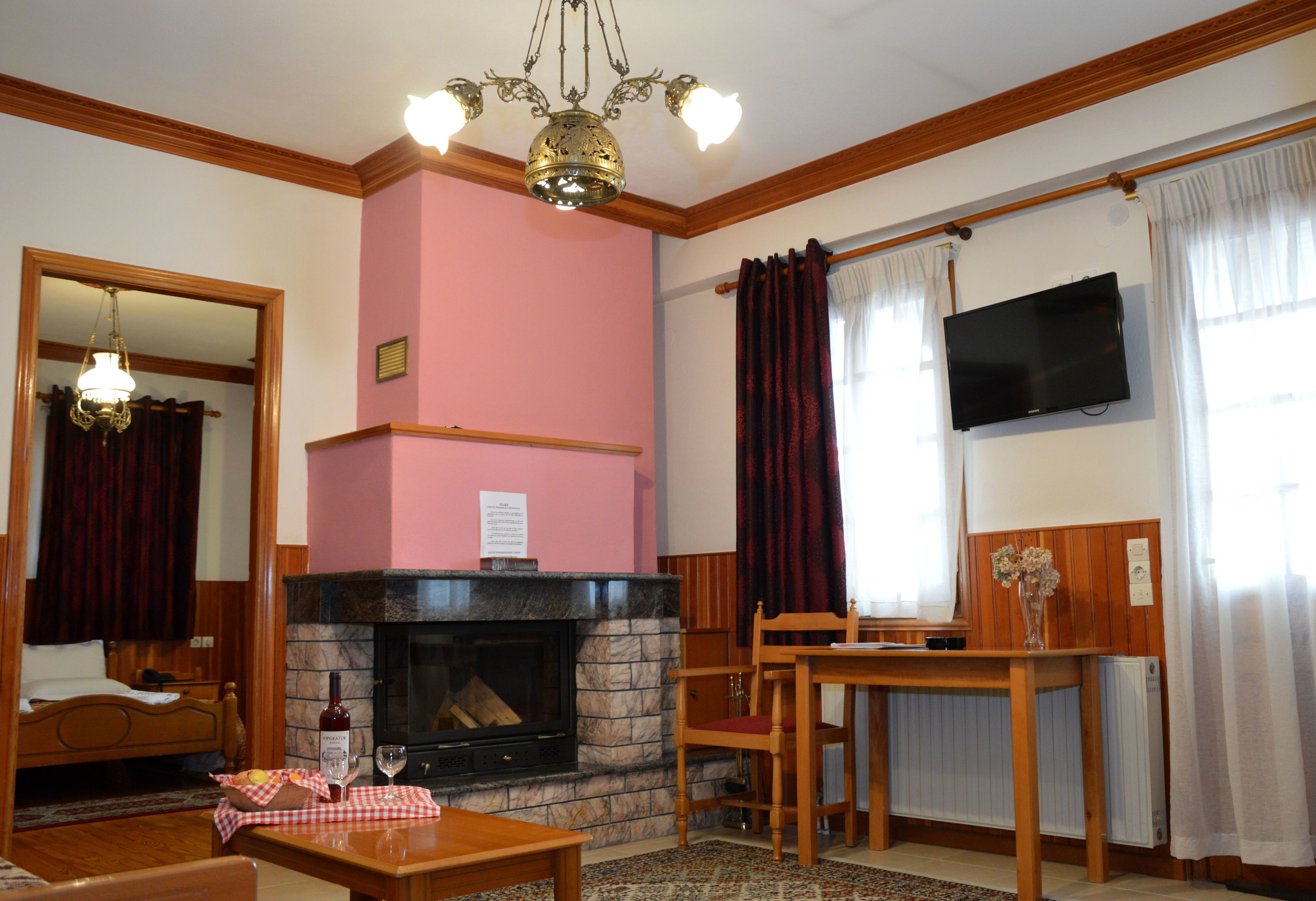 Ein gemütliches Wohnzimmer mit Kamin, einem an der Wand montierten Fernseher und einem Essbereich mit Tisch und Stühlen.