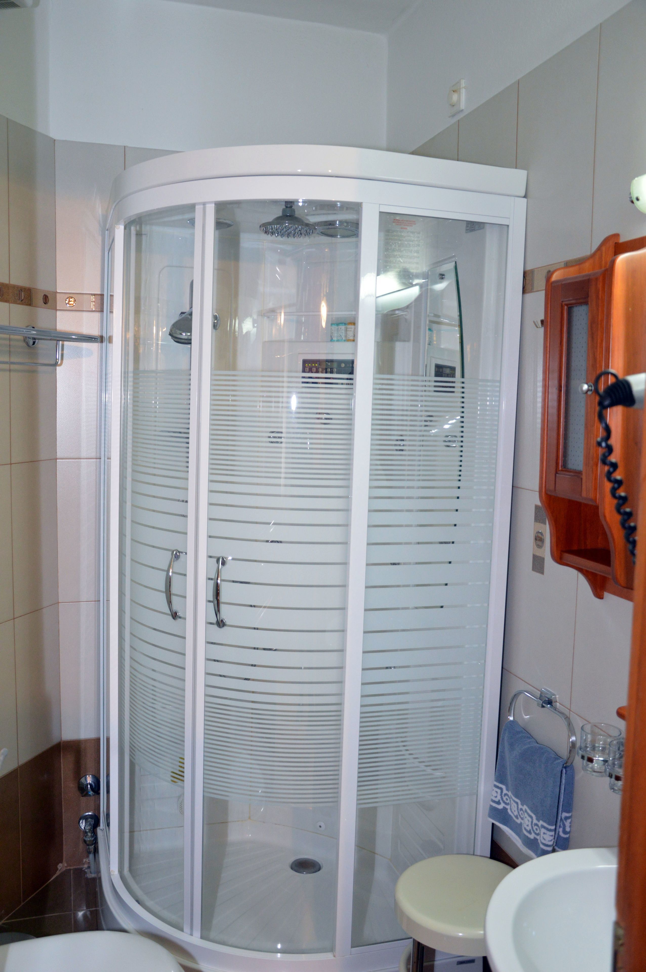 A bathroom with a glass-enclosed shower, a sink, and a mirror.