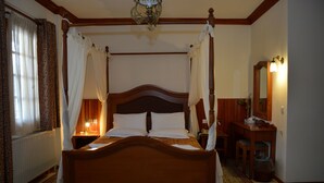 A four-poster bed with a wooden headboard, a nightstand with a lamp, and a mirror on the wall.