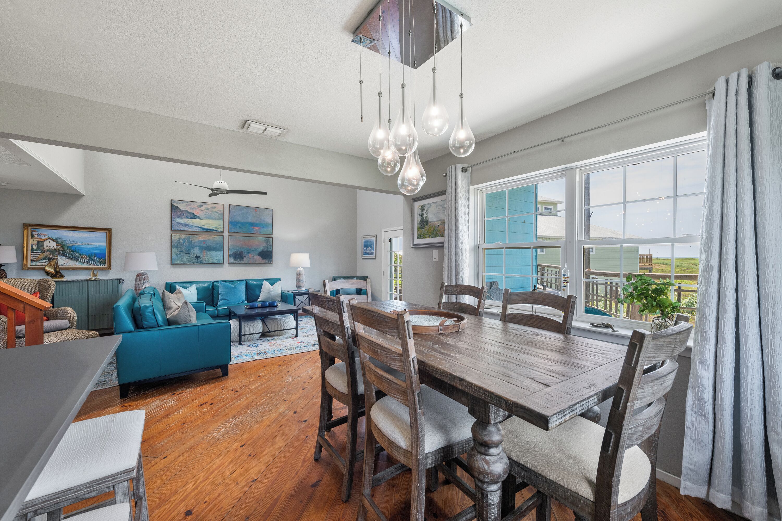 A spacious living area with a dining table, blue sofa, and artwork on the walls.