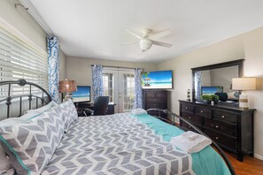 A hotel room with a bed, a desk, a dresser, a ceiling fan, and a TV. - You can truly enjoy the Port A lifestyle in this colorful home. Monthly rentals (Port Aransas)