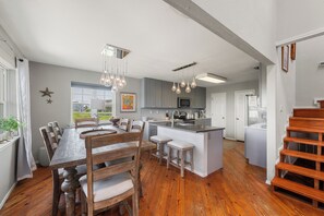 A spacious kitchen with a central island, wooden dining table, and bar stools.