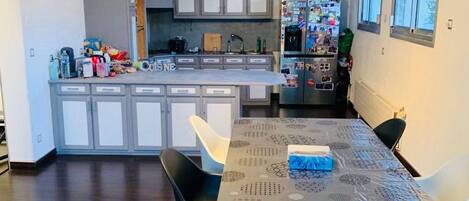 A modern kitchen with a central island, a dining table with chairs, and a refrigerator with magnets.