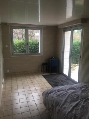 Un dormitorio con un ventanal grande, un escritorio pequeño y una cama.