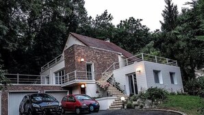 Una casa de dos pisos con fachada de ladrillo, un balcón y una entrada para dos coches.