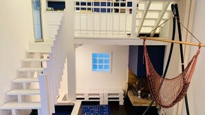 Una casa de muñecas con una escalera blanca, una hamaca y una ventana pequeña.