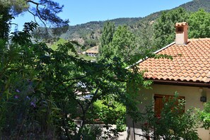 A house with a tiled roof, surrounded by greenery and hills in the background. - Kyveli Cottage (Foini)