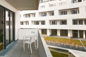 A modern building with multiple floors, large windows, and a courtyard with a small water feature and plants. - Lunas Appartements in Essen (Essen)