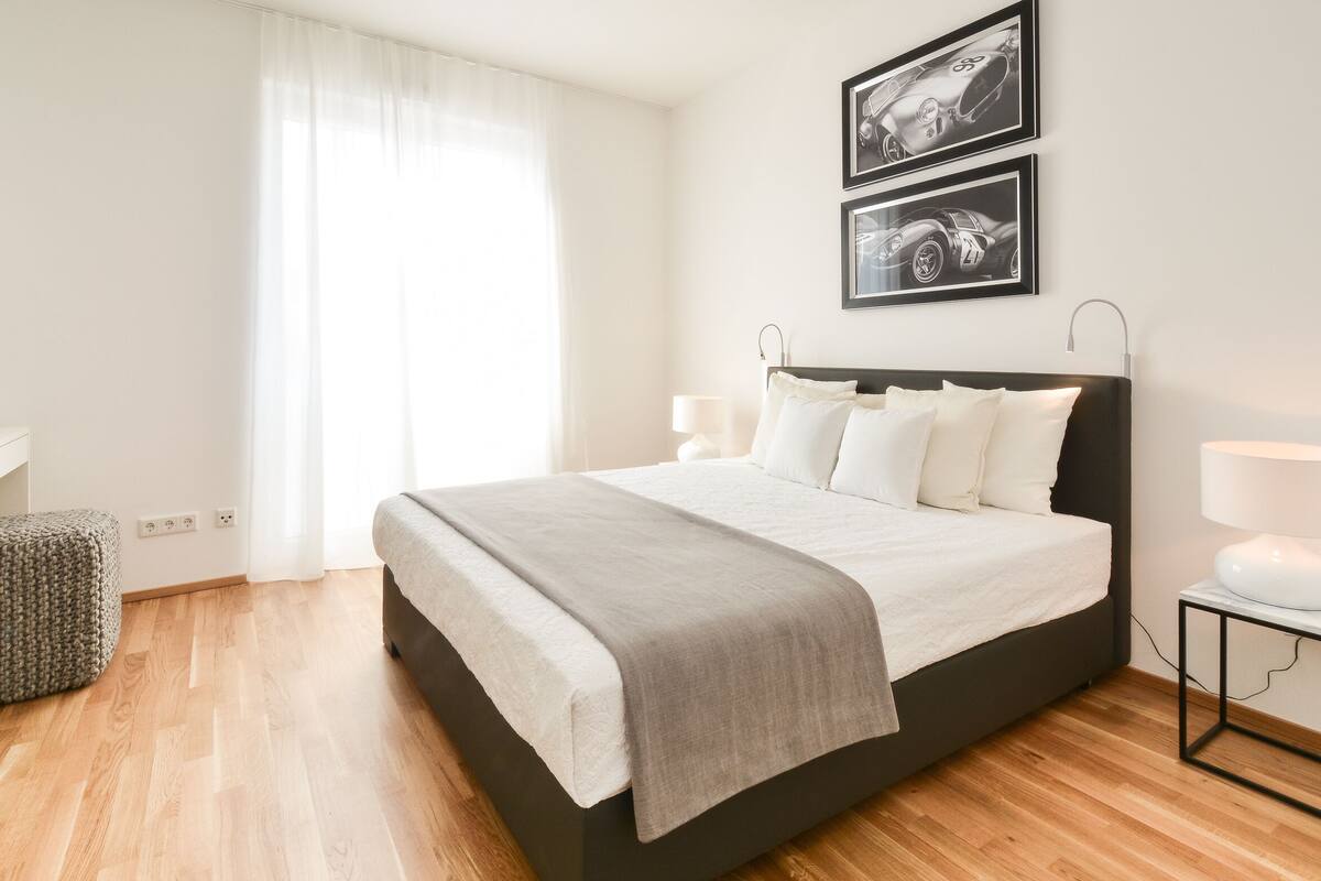 Quarto moderno com uma cama grande, abajures e duas fotos emolduradas na parede.