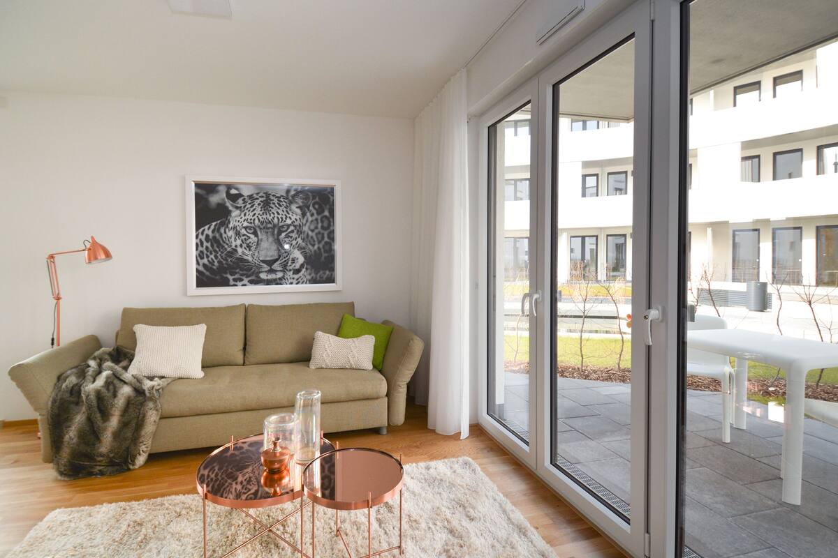 Uma sala de estar moderna com um sofá, um tapete estampado com onças e uma mesa de vidro com velas.
