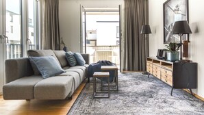 A modern living room with a grey sofa, a small wooden table, and a black cabinet. - Lunas Appartements in Essen (Essen)