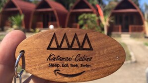 Un llavero de madera con el texto "Kintamari Cabins Sleep, Eat, Trek, Swim".
