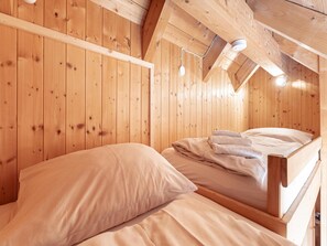 A wooden cabin room with two beds, a sloped ceiling, and a visible light fixture. - Snug Holiday Home in Sankt Georgen ob Murau near Kreischberg (Sankt Georgen am Kreischberg)