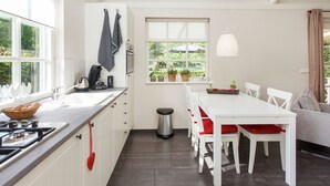 A modern kitchen with white cabinets, a gas stove, and a window overlooking greenery. - Holiday Home in Ravenstein With Garden (Overlangel)