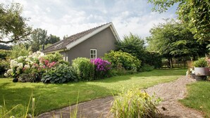 A house with a sloped roof, surrounded by a well-maintained garden with various plants and flowers. - Holiday Home in Ravenstein With Garden (Overlangel)