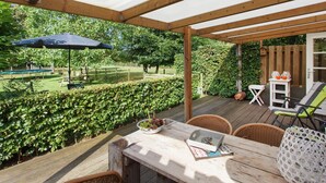 A covered patio with a wooden table, chairs, and a small table with decorative items. - Holiday Home in Ravenstein With Garden (Overlangel)