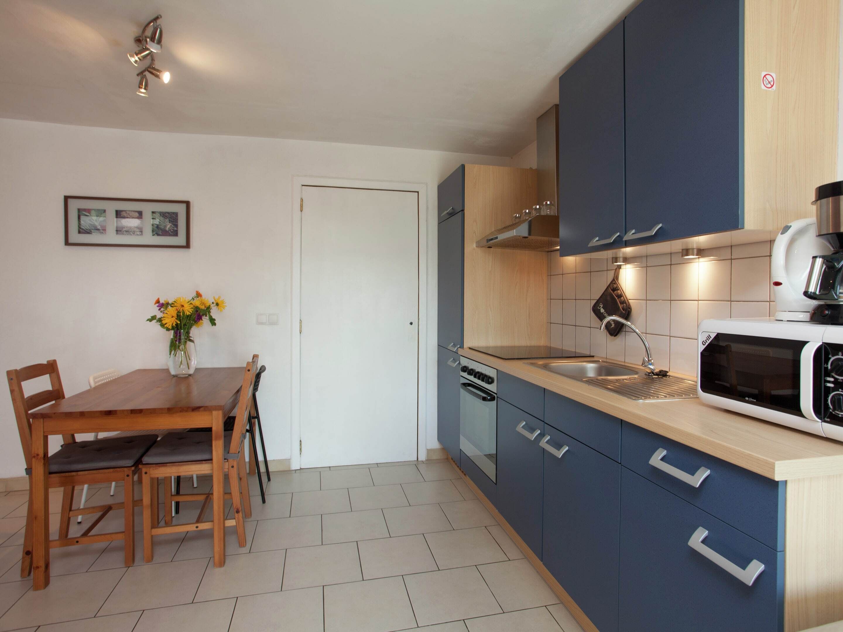 Une cuisine moderne avec des meubles en bois, un four à micro-ondes encastré et un coin repas comprenant une table et des chaises.