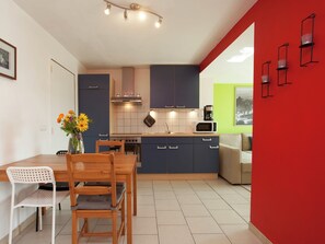 Una cocina moderna con comedor, que incluye una mesa de madera, sillas, un jarrón con flores y una pared decorada en rojo.