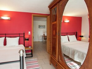 Habitación de hotel con dos camas, un armario de madera, un espejo y una pared roja.