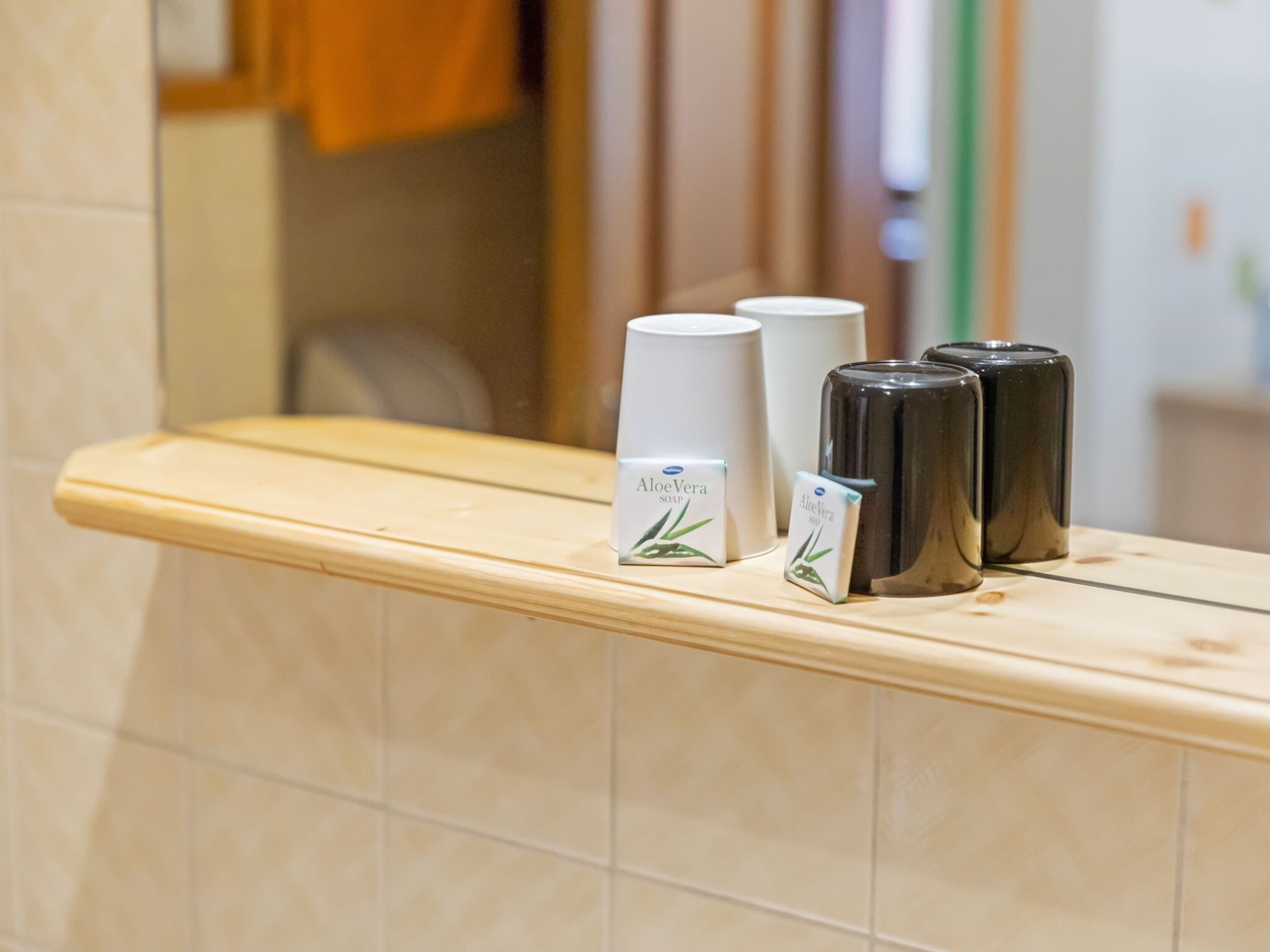 A bathroom counter with toiletries including a white bottle labeled 'Aloe Vera Soap' and three black bottles.