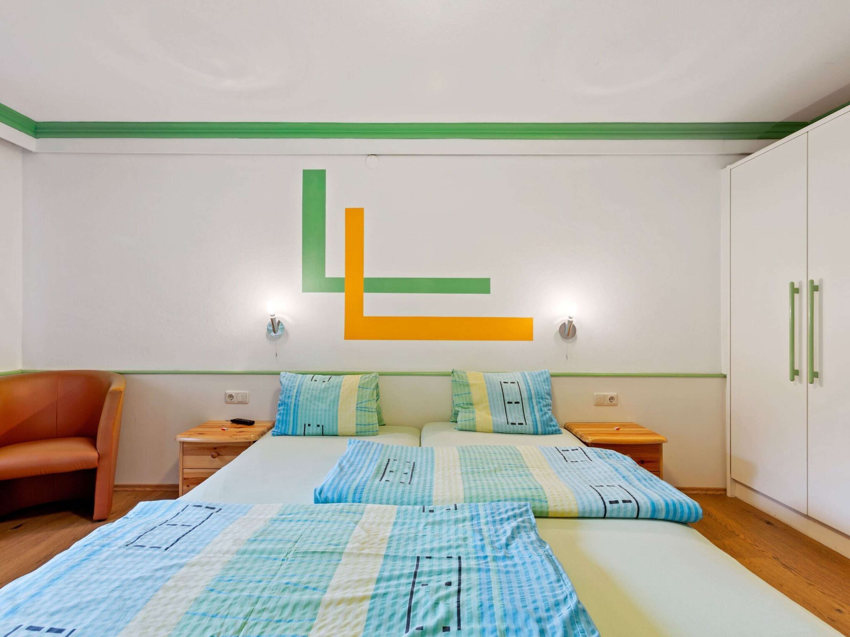 A bedroom with a bed, two nightstands, a chair, and a wardrobe.