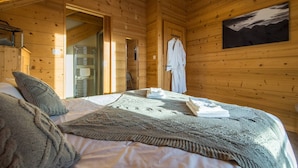 Ein Schlafzimmer einer Holzhütte mit Bett, Fenster und einem Bild an der Wand.
