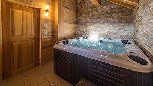 Eine Holzhütte mit Whirlpool, Holzwänden und einer Steinwand.