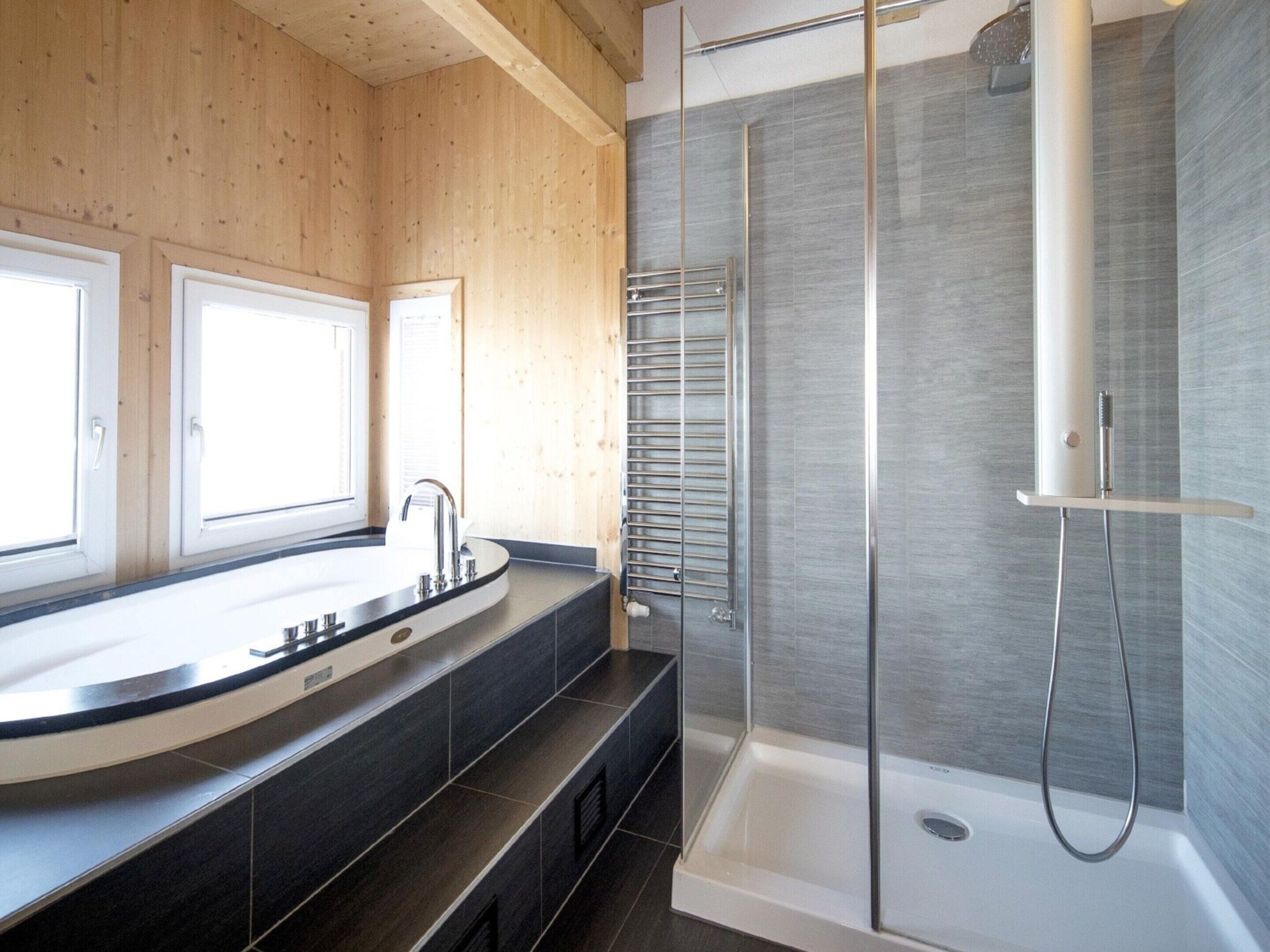 A modern bathroom with a large sink, a glass shower enclosure, and wooden walls.
