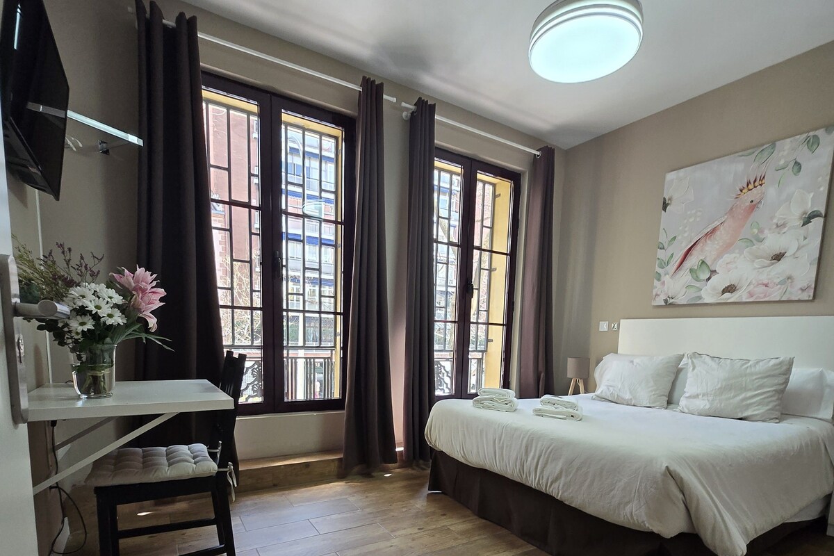 Un dormitorio con cama, escritorio y ventana con cortinas.