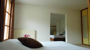 A hotel room with a bed, a radiator, a mirror, and a wardrobe.