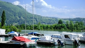 A marina with boats docked, surrounded by lush greenery and hills. - Hotel Restaurant Les Bergeronnettes (Champagneux)