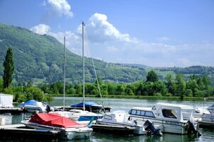 Un port de plaisance où sont amarrés des bateaux, entouré d’une végétation luxuriante et de collines.