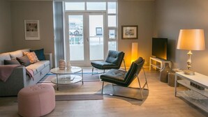 Un salon moderne comprenant un canapé, deux fauteuils, une table basse et un téléviseur.