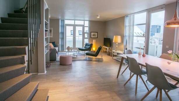 Un grand espace de vie comprenant un escalier, une table à manger avec des chaises, un canapé et une lampe.