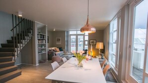 Un salon moderne avec une table à manger, un escalier et une grande fenêtre.