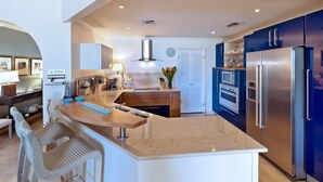 Una cocina moderna con una isla central, electrodomésticos de acero inoxidable y armarios azules.