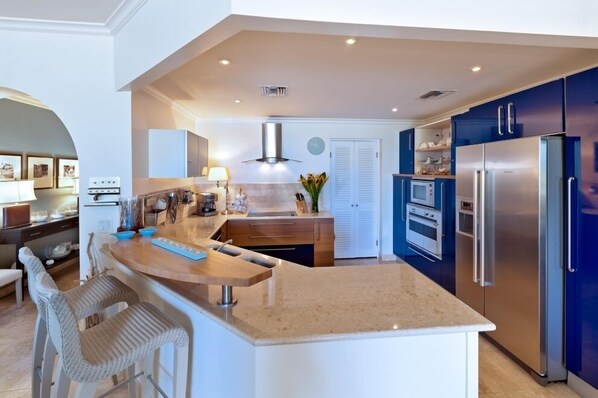 A modern kitchen with a central island, stainless steel appliances, and blue cabinetry.