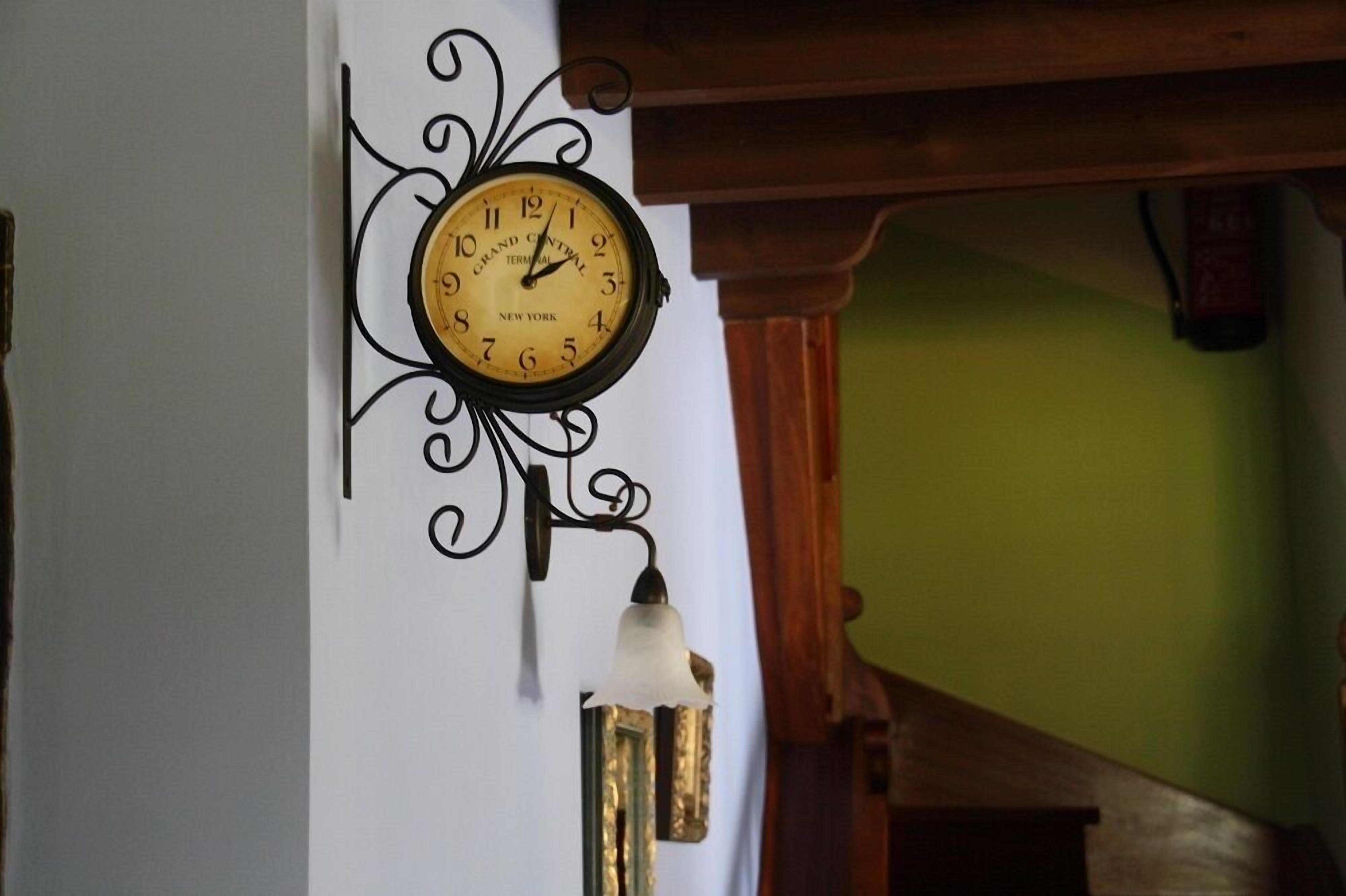 Un reloj de pared con diseño clásico, con marco negro y esfera blanca con números y agujas negras.