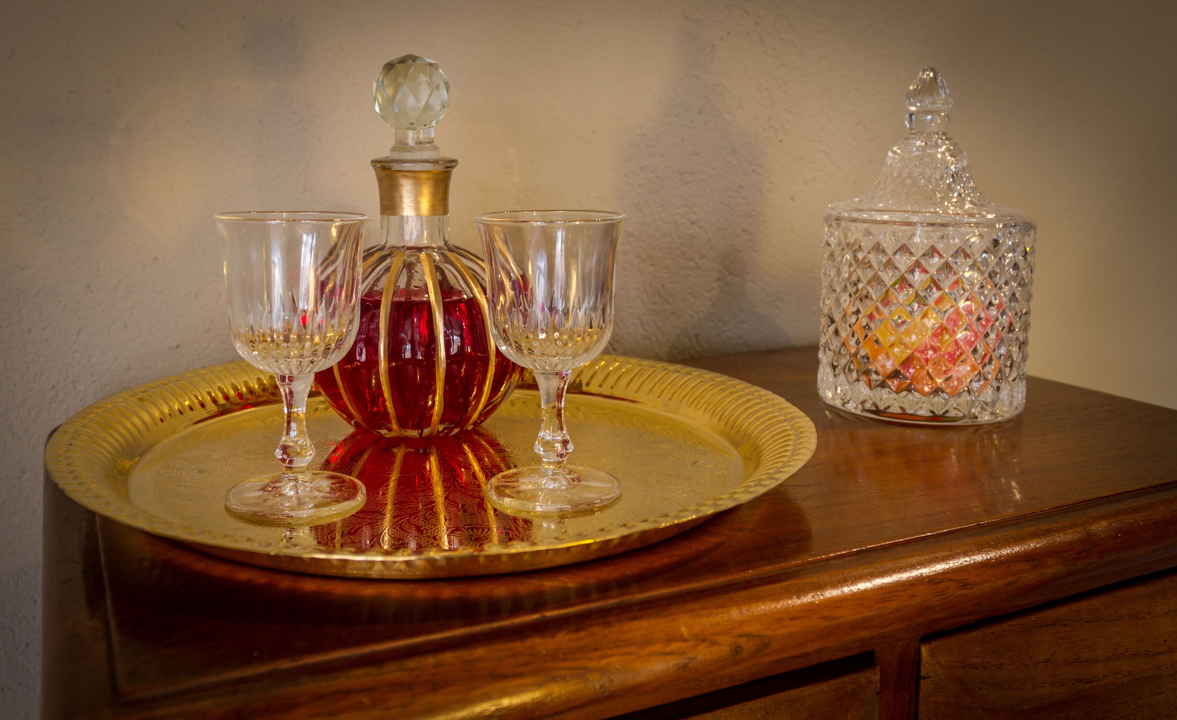 Un plateau avec une carafe en cristal et trois verres, posé sur une table en bois.