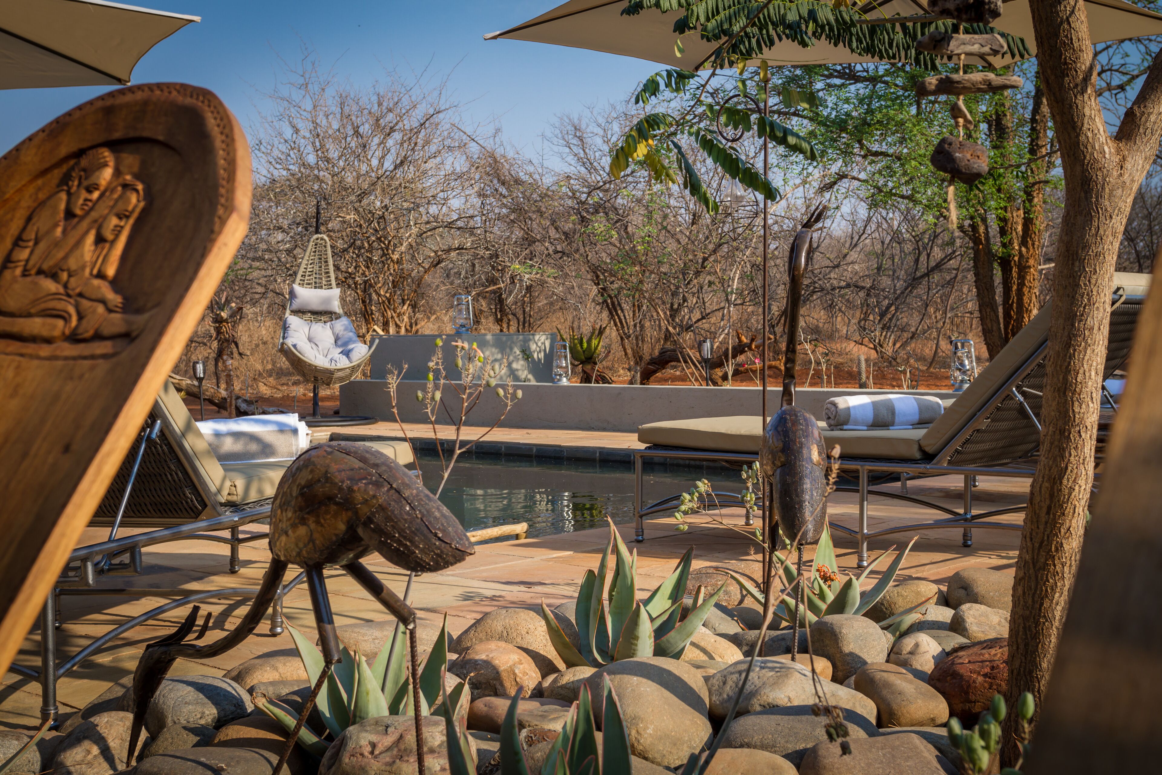 A poolside area with a hot tub, lounge chairs, and a hanging chair.