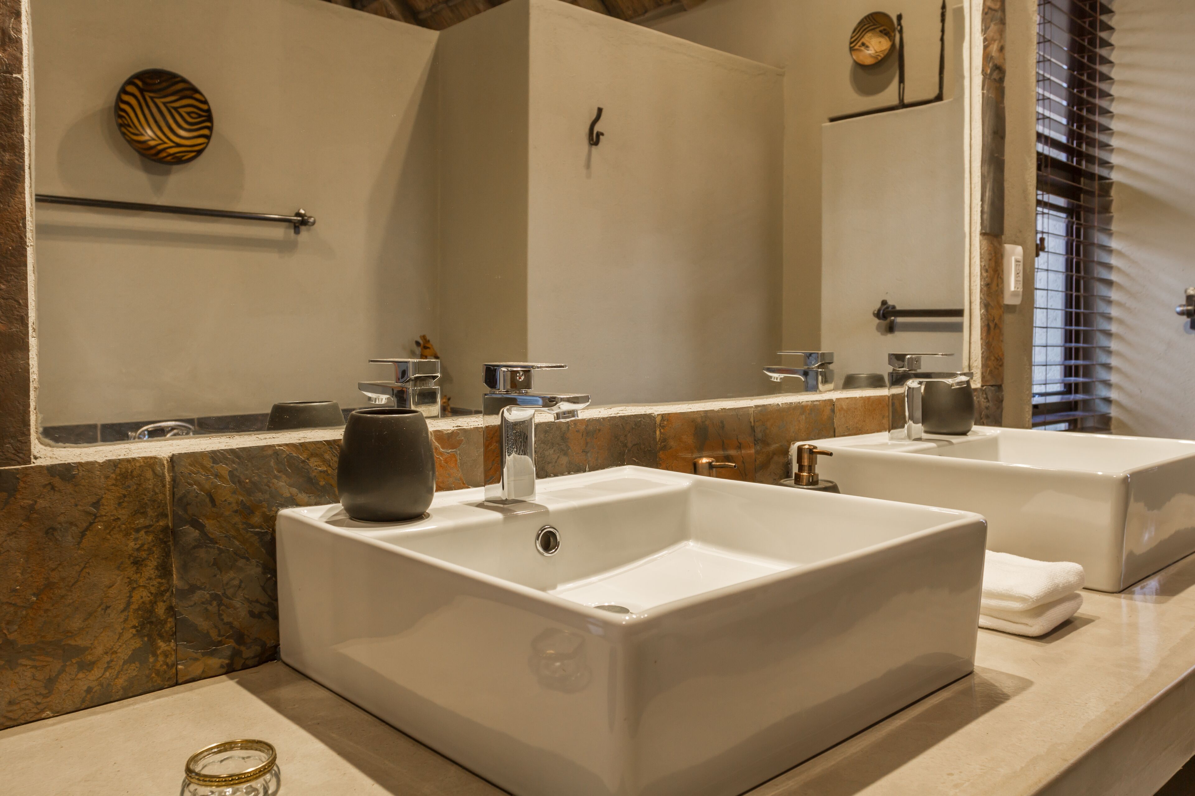 Un baño moderno con dos lavamanos grandes blancos, una encimera de mármol y un espejo amplio.