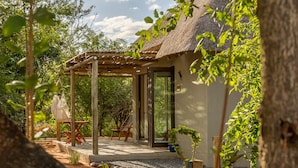 A modern house with a thatched roof, a covered outdoor seating area, and a gravel pathway. - Ukuthula Bush Lodge (Hoedspruit)
